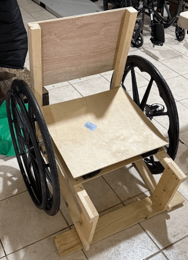 Nearly complete wheelchair in late-stage assembly showing progression toward the finished product